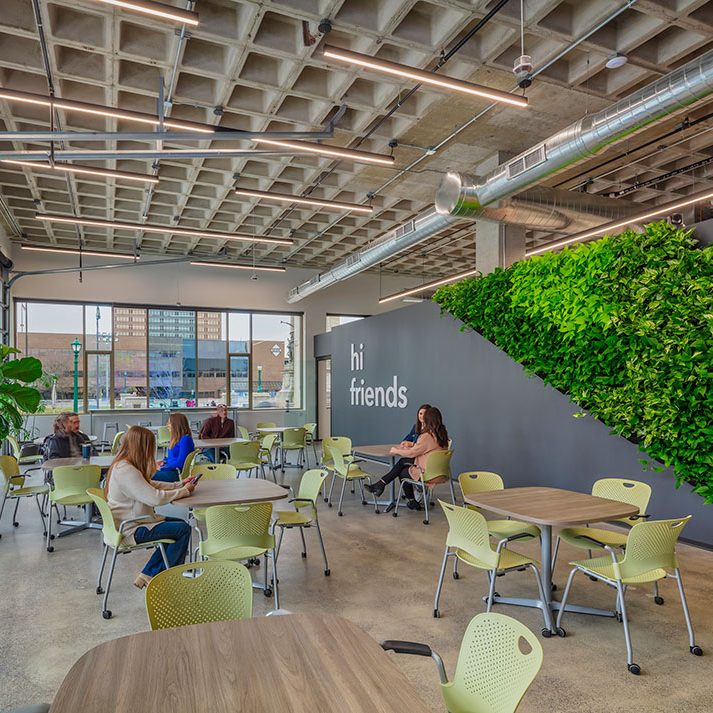 Meeting space/cafeteria/breakroom with green living wall, tables and rolling chairs